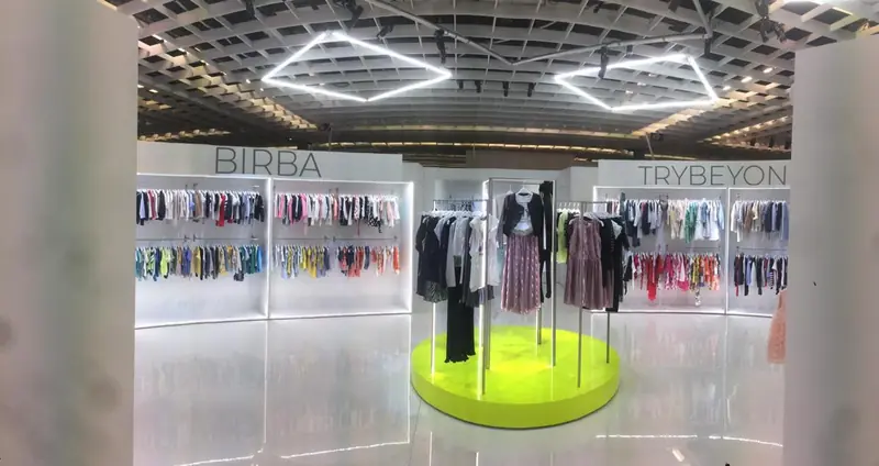 Stand con abbigliamento appeso e tavolo rotondo giallo