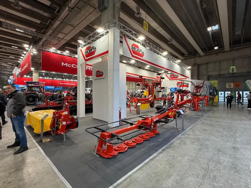 Stand rosso con macchine agricole esposte in un padiglione fieristico