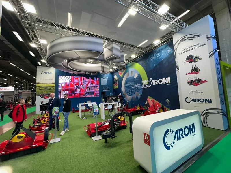 Stand Aroni con soffitto circolare, schermo e macchine su prato sintetico