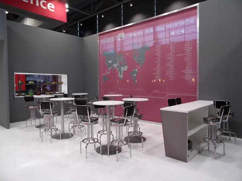 Stand grigio con tavolini alti e mappa del mondo rosa