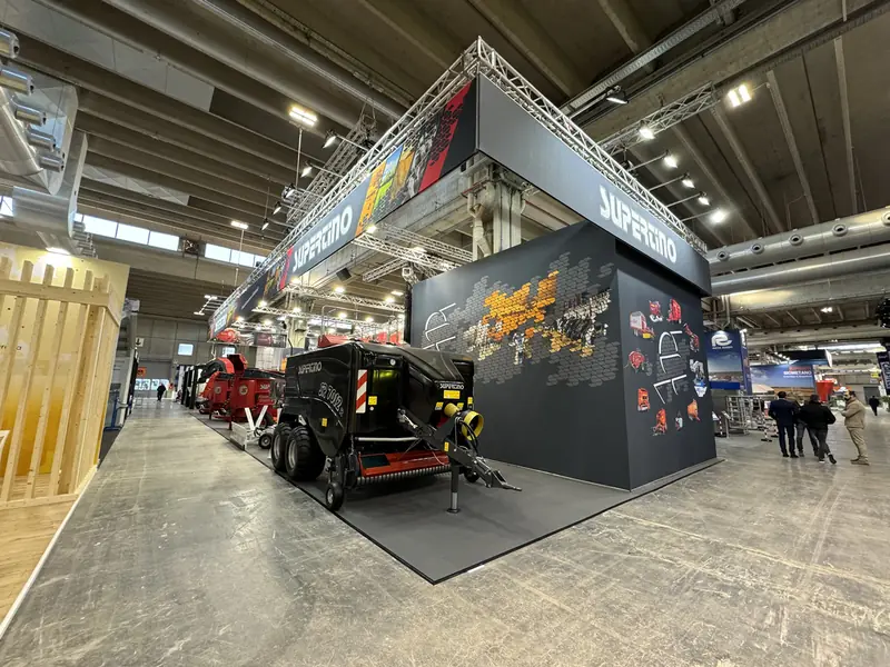 Stand con struttura grigia e trattore nero in padiglione