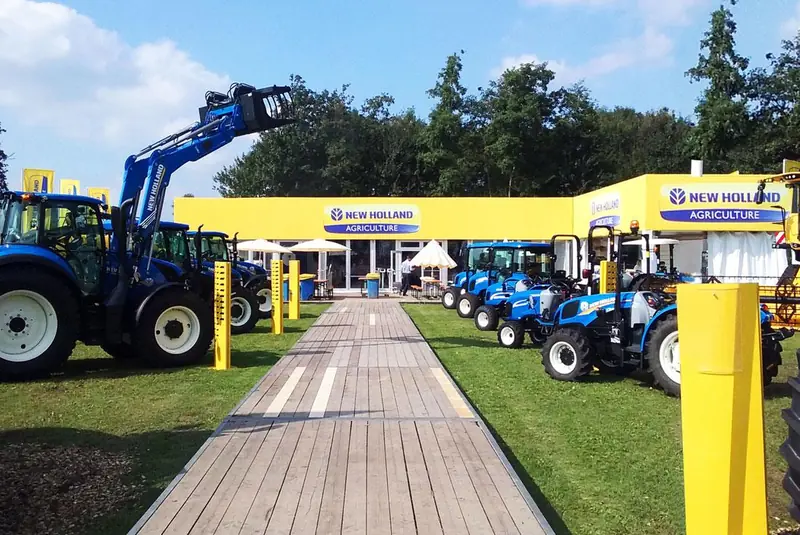 Area New Holland con trattori blu e passerella in legno