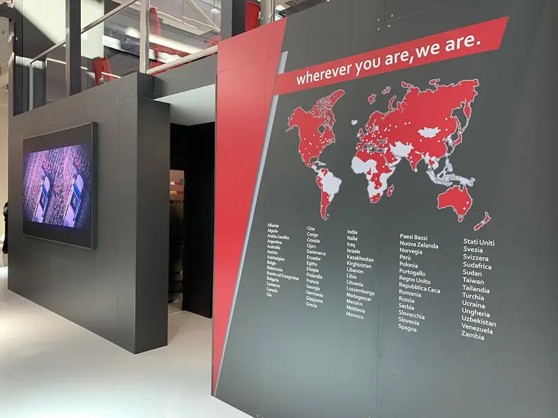 Parete grigia con mappa del mondo rossa e scritta "wherever you are, we are"