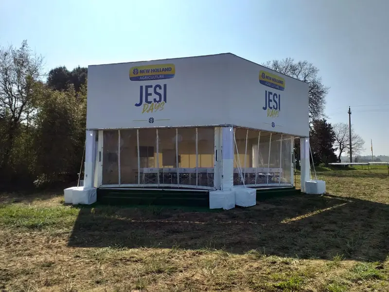 Struttura bianca vetrata con logo Jesi New Holland in un campo