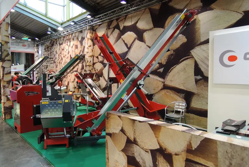 Stand con spaccalegna rosso e parete di tronchi