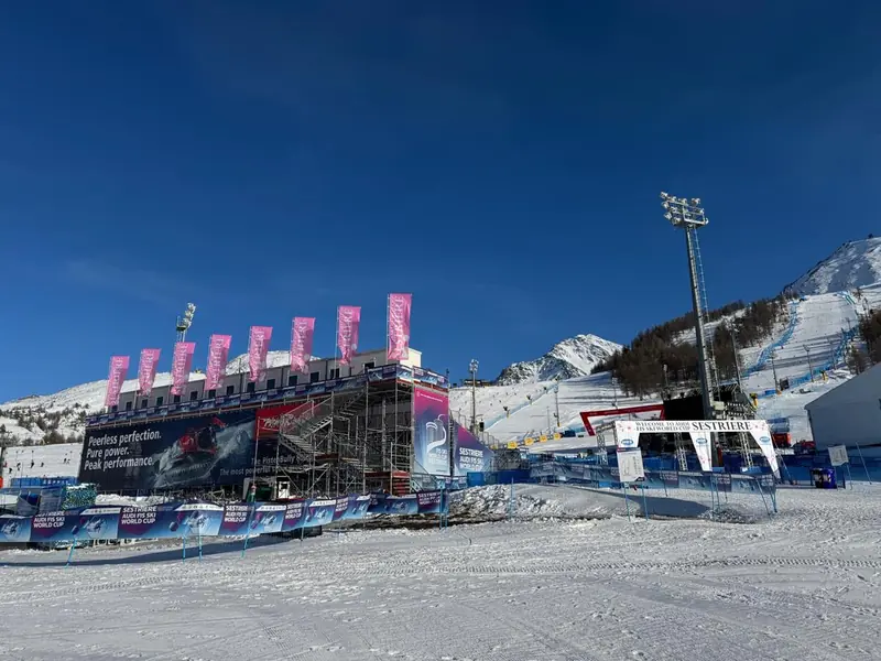 Struttura con bandiere rosa e impalcature sulla neve, con le montagne sullo sfondo