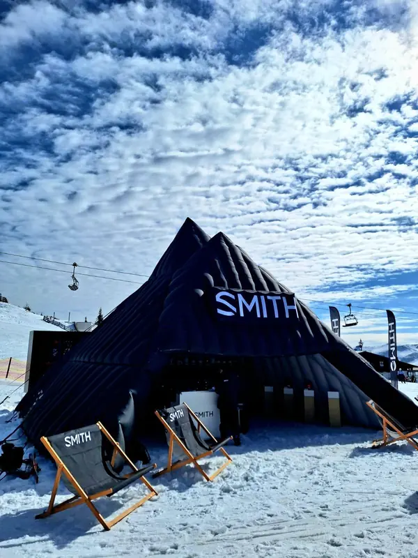 Tenda scura a punta con logo Smith sulla neve, con sdraio