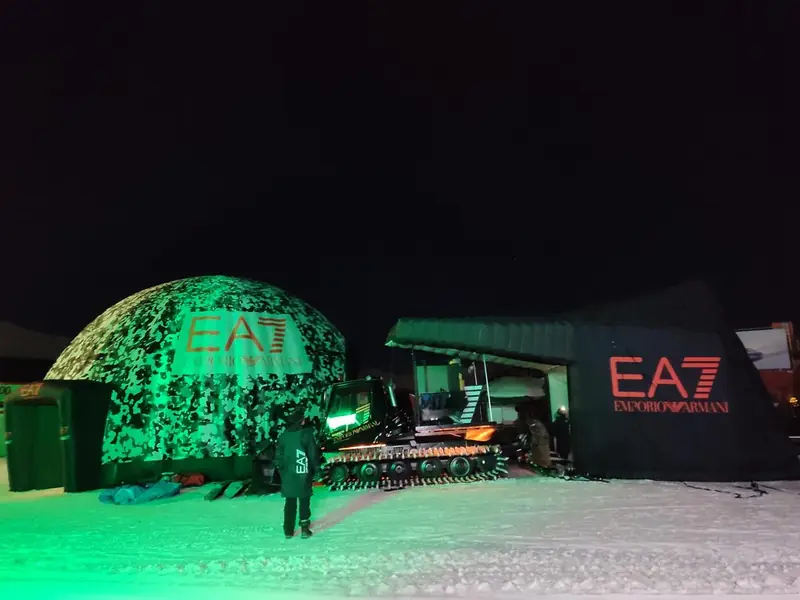 Cupola verde illuminata di notte con logo EA7 e mezzo battipista