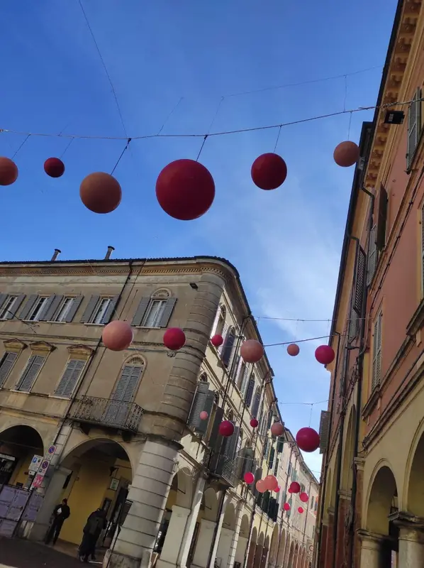 Sfere rosse sospese sopra una via con portici