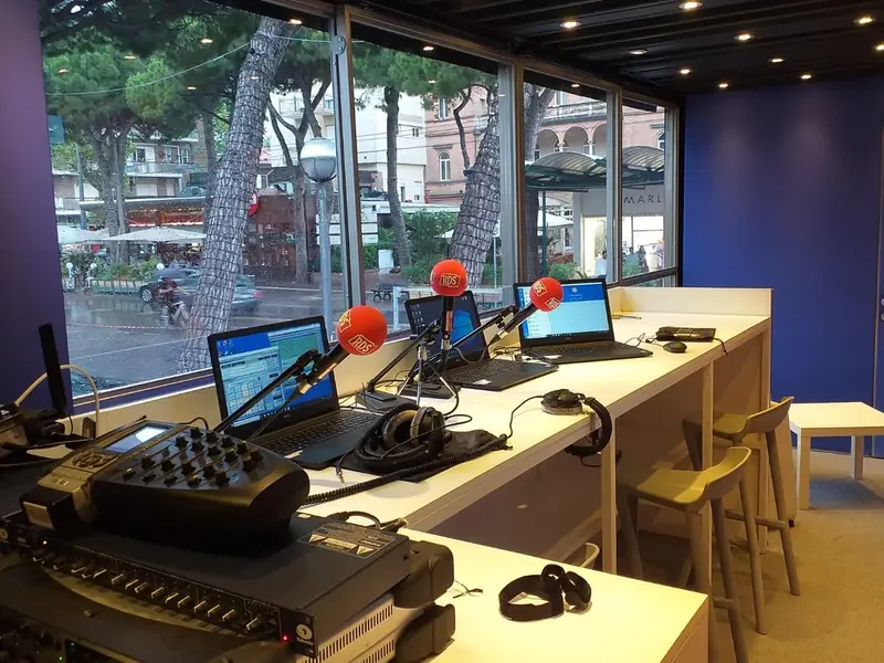Studio radio con microfoni, mixer e portatili dietro grandi vetrate