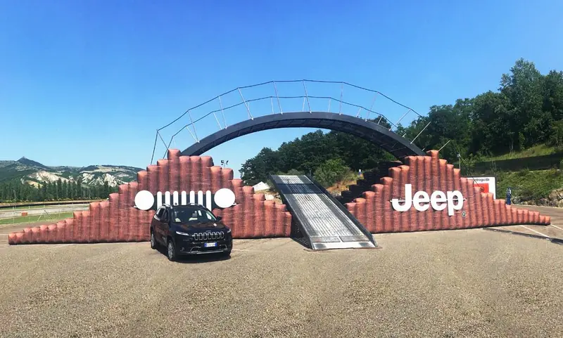 Struttura rossa con rampa e logo Jeep con auto esposta