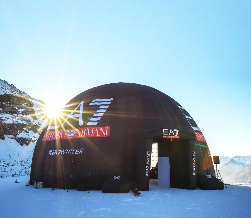 Cupola nera Emporio Armani EA7 con il sole alle spalle in montagna