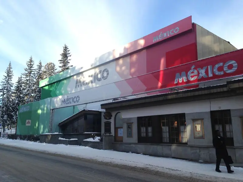 Edificio con facciata bianca, rossa e verde con la scritta México, innevato