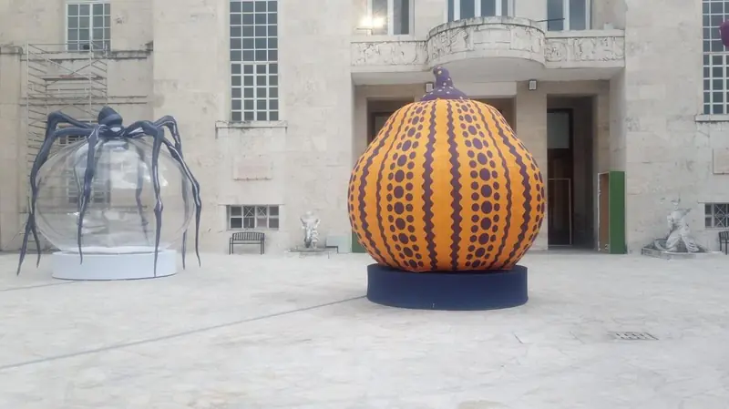 Zucca gonfiabile gialla a pois e ragno gigante in una piazza
