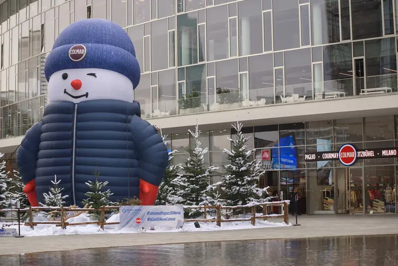 Pupazzo di neve gonfiabile gigante con piumino davanti a un edificio