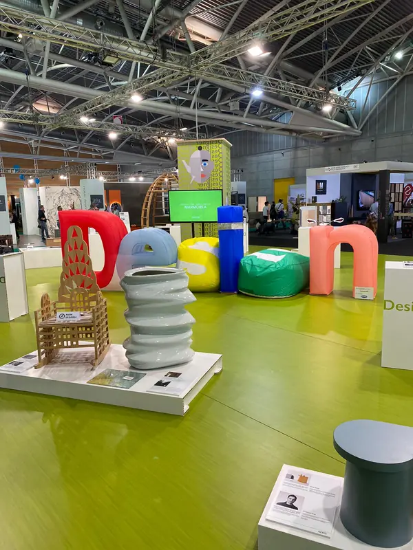 Lettere gonfiabili "Design" e personaggio su pavimento verde in fiera