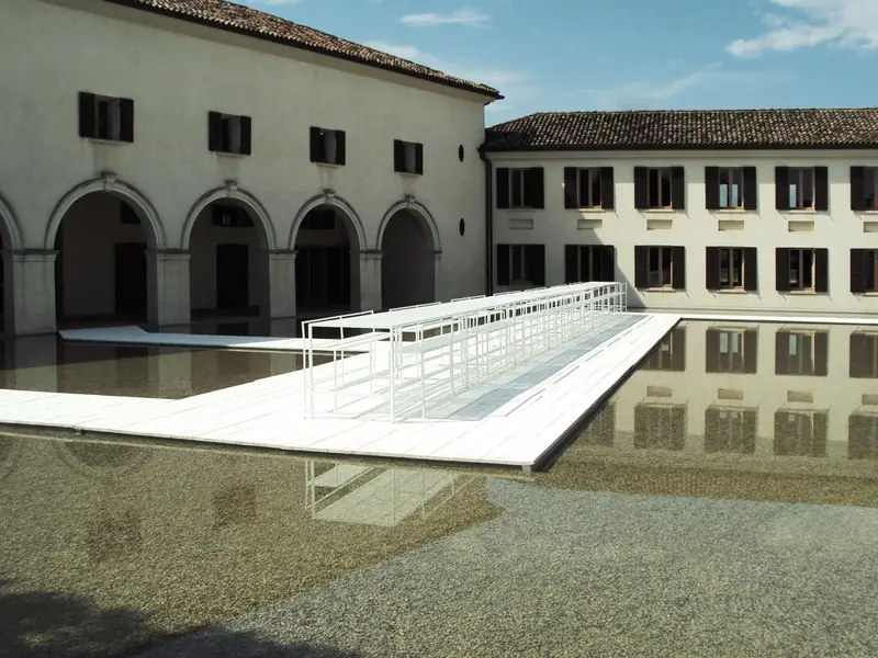 Passerella bianca sopra una vasca d'acqua in un cortile con portici