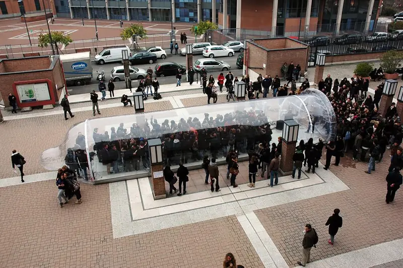 Tunnel trasparente affollato in una piazza, visto dall'alto