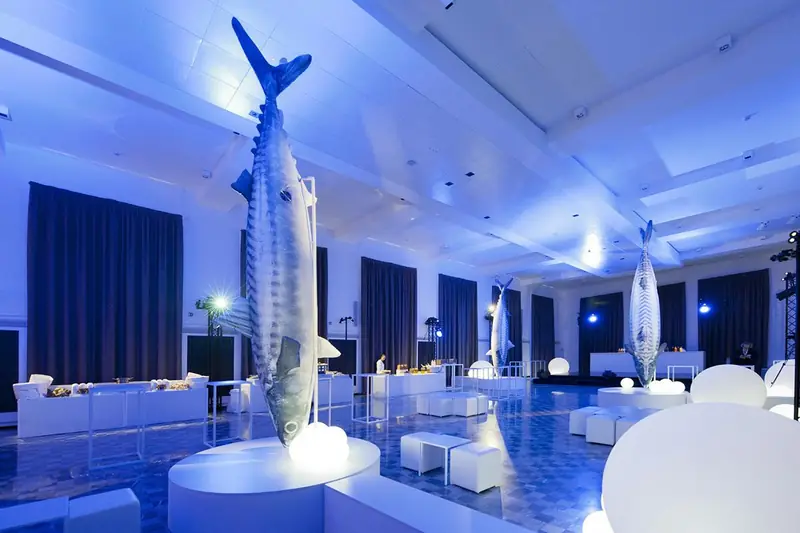 Pesci giganti in una sala blu illuminata durante un evento