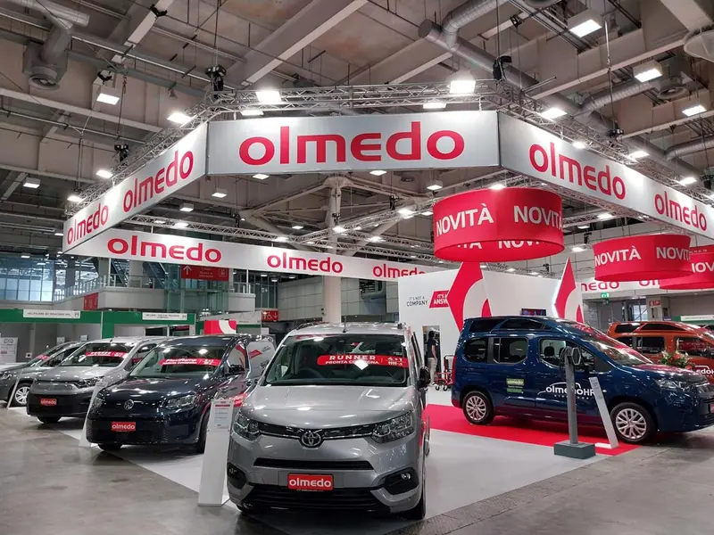 Stand Olmedo con veicoli commerciali e insegne rosse