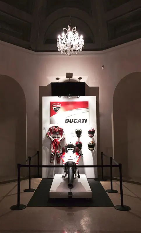 Moto Ducati esposta in una sala storica con lampadario