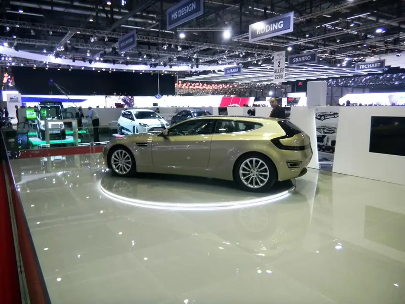 Auto dorata su piattaforma luminosa in un salone dell'auto
