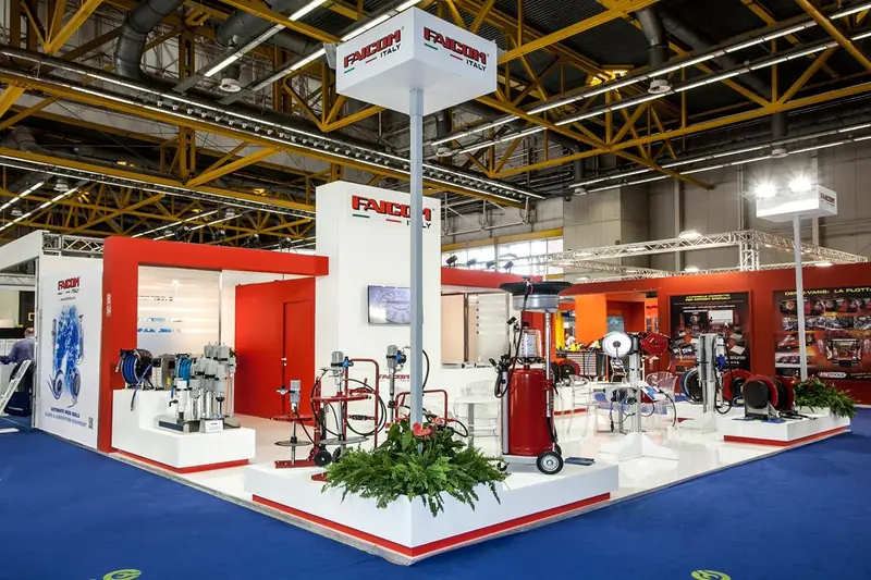 Stand con attrezzature esposte, struttura bianca e rossa e moquette blu