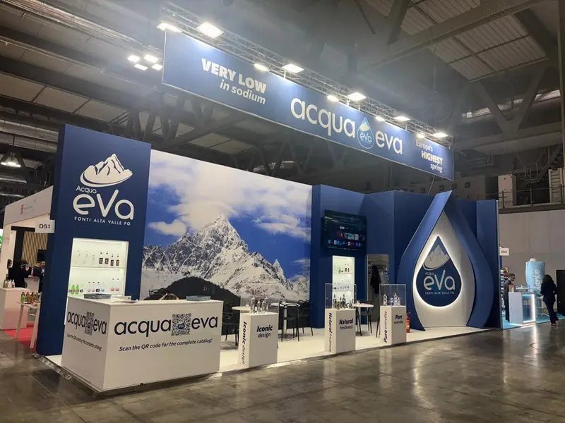 Stand Acqua Eva con grafica di montagne e insegna blu