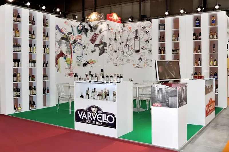 Stand Varvello con scaffali di bottiglie e tappeto verde