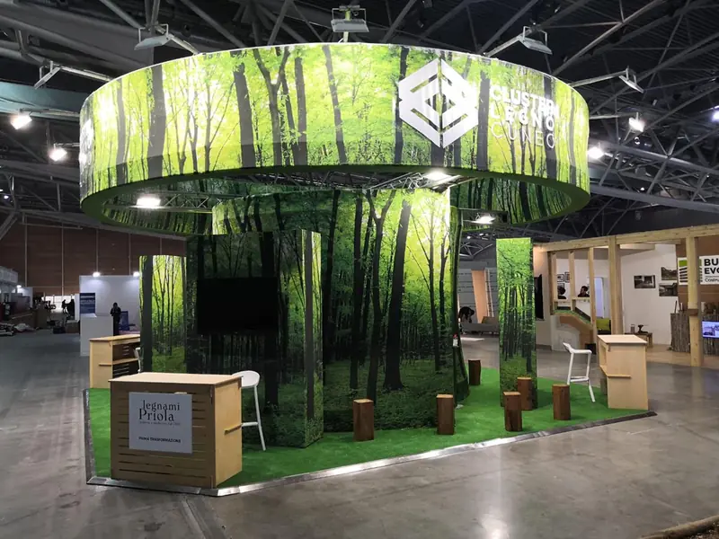 Stand circolare con grafiche di bosco e prato sintetico