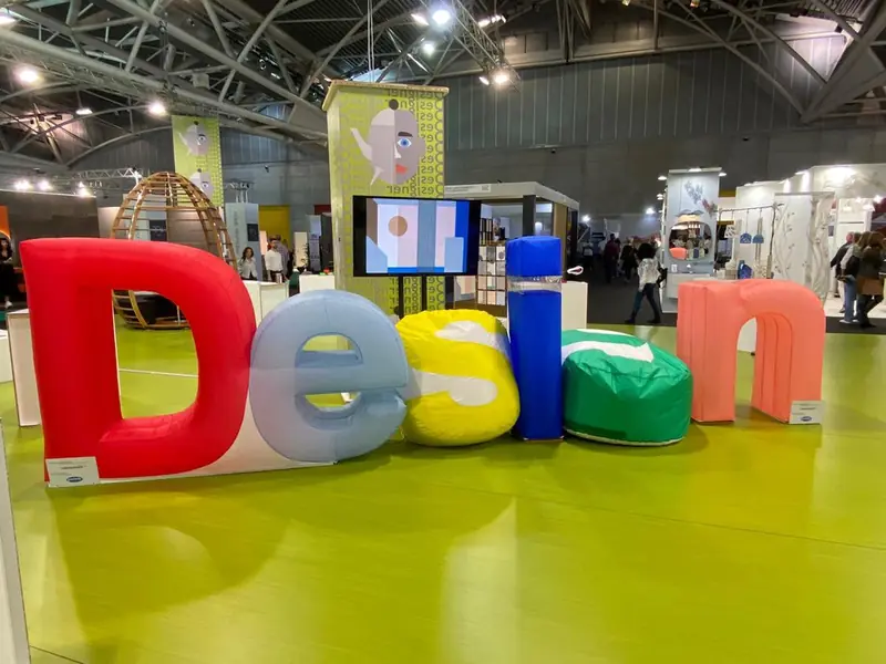 Lettere colorate "Design" su pavimento verde in una fiera
