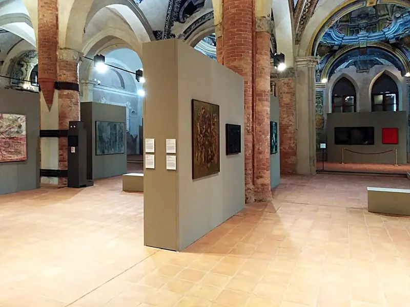 Mostra di dipinti in una chiesa con pannelli espositivi grigi