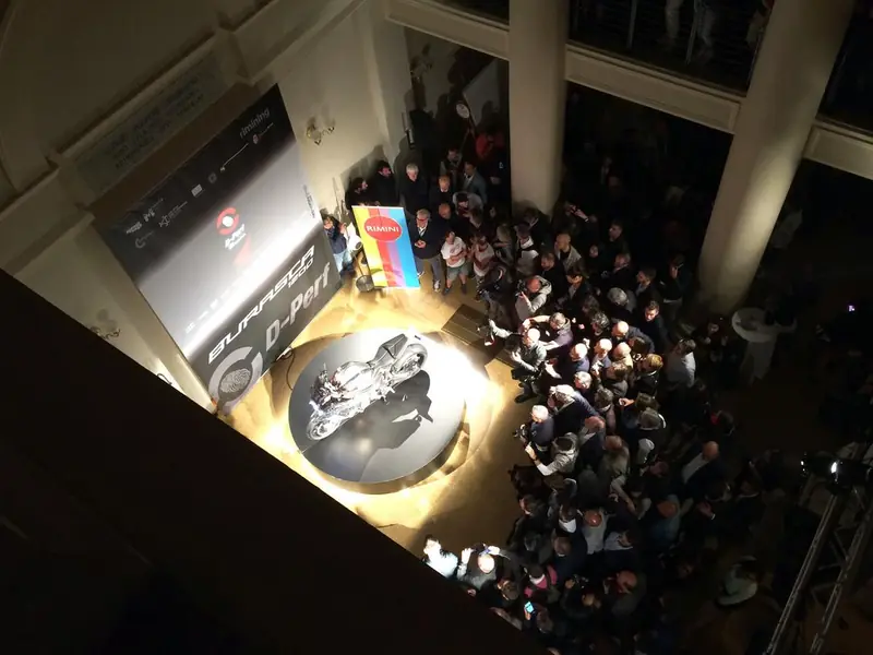 Evento con folla riunita attorno a un'auto da corsa, visto dall'alto