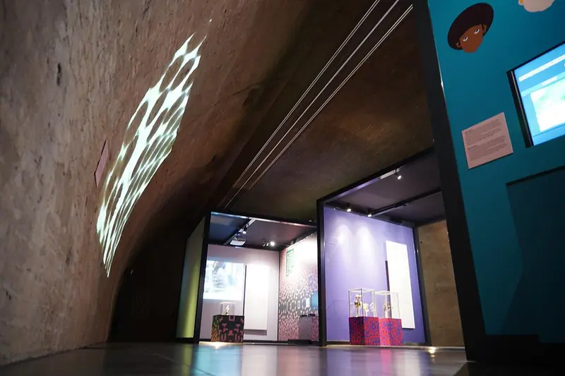 Percorso espositivo in una sala con volta con proiezioni e vetrine, vista dal basso