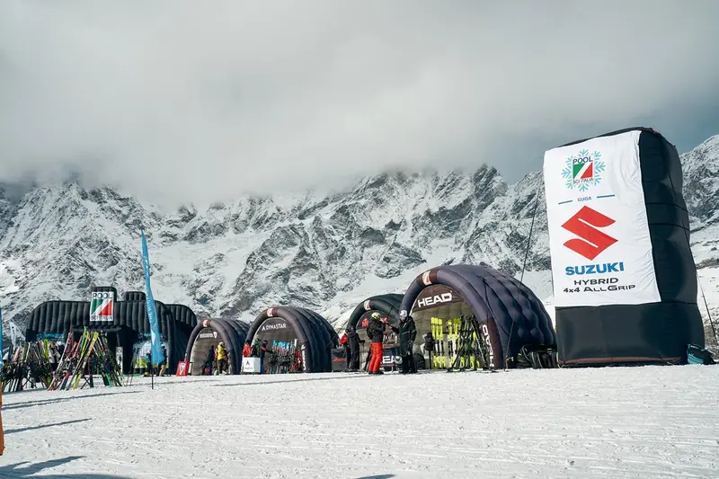 Tende gonfiabili scure e totem Suzuki davanti alle montagne innevate