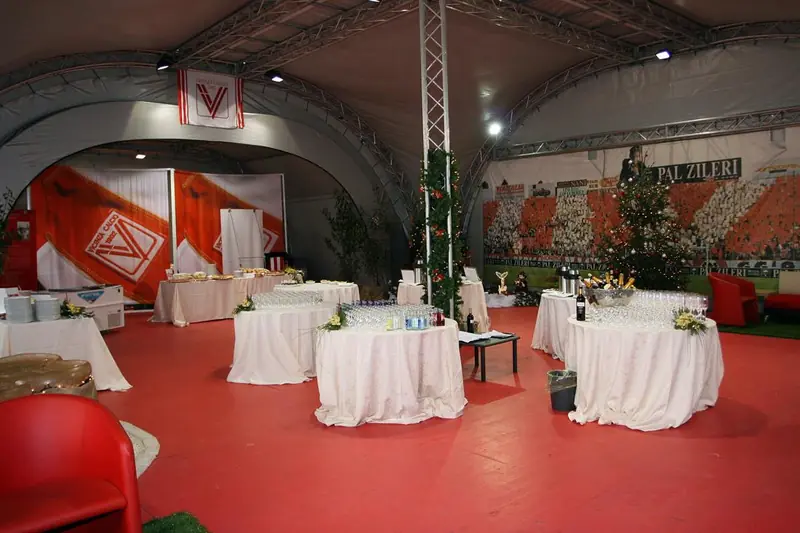 Sala con tavoli apparecchiati e pareti grafiche rosse sotto un tendone