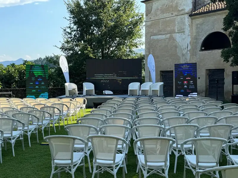 Sedie bianche e palco allestiti in un giardino davanti a un edificio storico