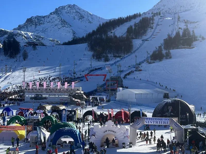 Villaggio sulle piste da sci con tende, archi gonfiabili e montagne sullo sfondo