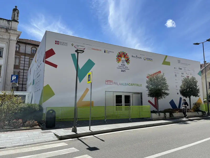 Padiglione temporaneo bianco con grafiche colorate lungo una strada