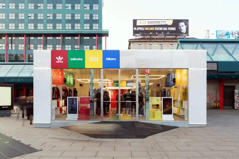 Negozio temporaneo Adidas con vetrate e riquadri colorati in una piazza