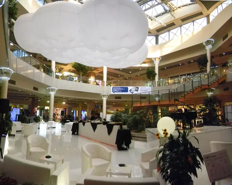 Area lounge con arredi bianchi e nuvola gonfiabile in un centro commerciale