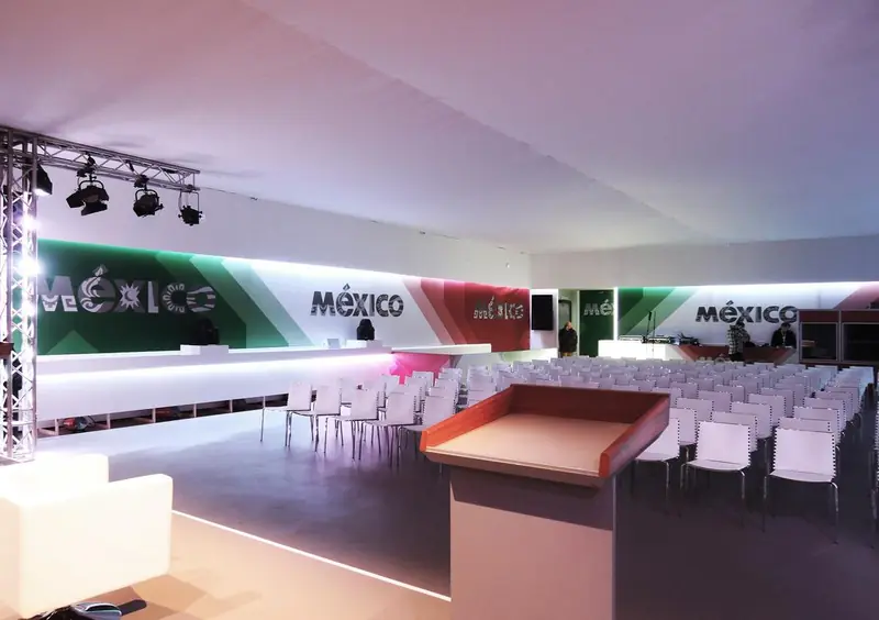 Sala convegni con sedie bianche e pareti grafiche México