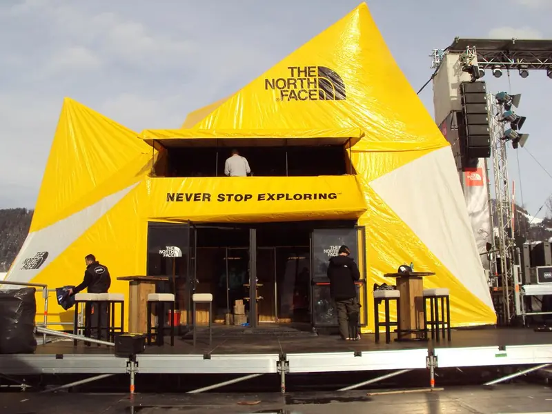 Struttura gialla The North Face con soppalco e tavolini alti